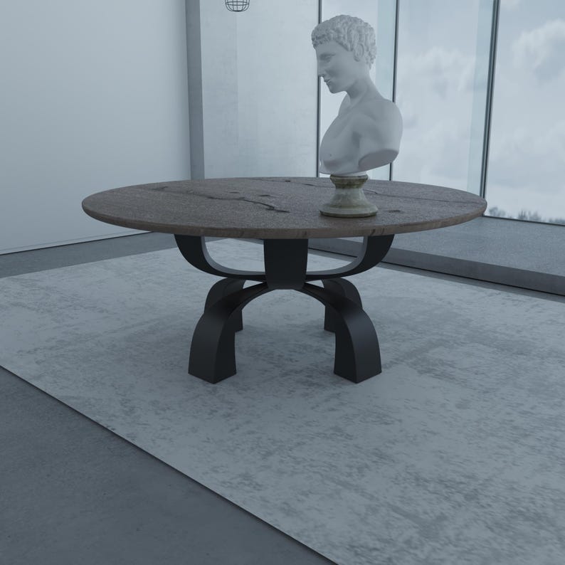 May include: A round wooden dining table with a dark brown top and a black metal base. The table has a unique, curved base design. A white plaster bust of a man is sitting on the table.