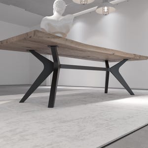 May include: A large, rectangular wooden dining table with a natural finish. The table is supported by black metal legs with a unique, angular design. The table is approximately 10 feet long.