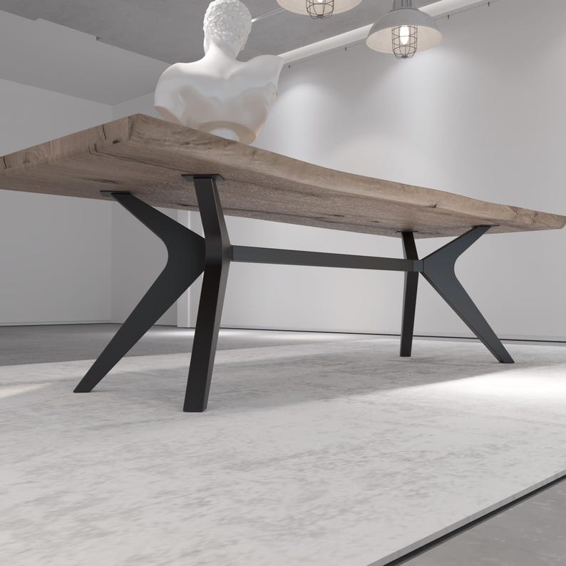 May include: A large, rectangular wooden dining table with a natural finish. The table is supported by black metal legs with a unique, angular design. The table is approximately 10 feet long.