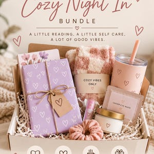 May include: A gift box containing a book wrapped in purple heart-patterned paper with a tag, fuzzy pink and white checkered socks, a pink tumbler with a straw, a small candle, a pink scrunchie, a lip balm, and an under eye mask packet.