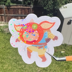 May include: A die-cut holographic sticker featuring a cartoon character wearing a bright orange pig-shaped hood with green accents. The character has a blue shirt, yellow pants, and brown boots, depicted in a dynamic running pose with a holographic finish.