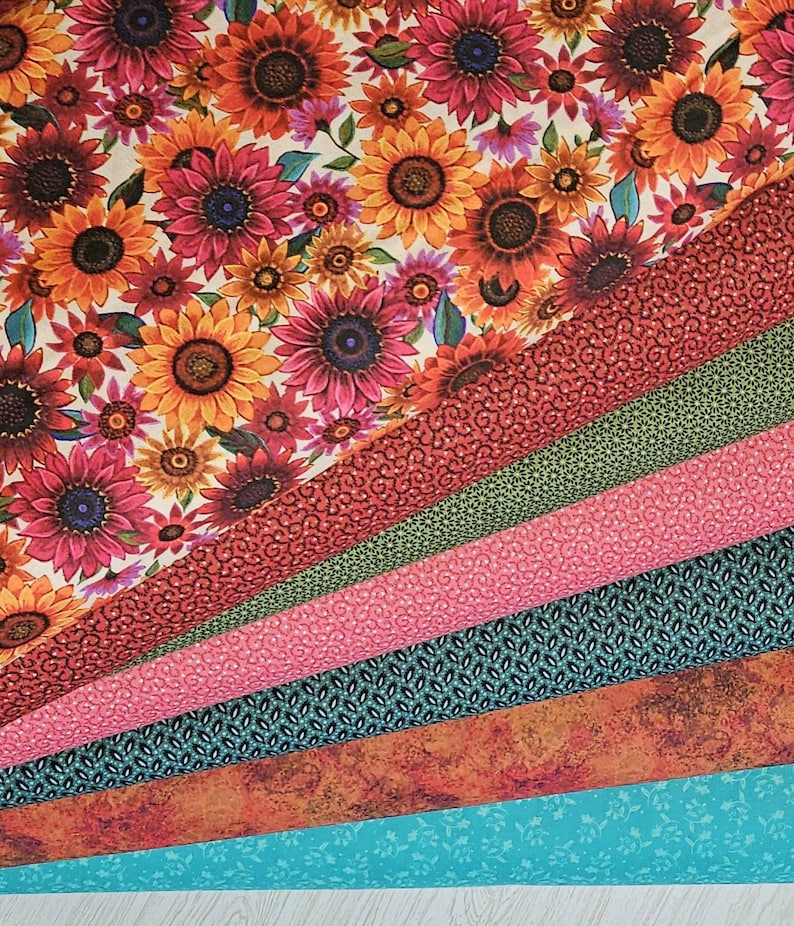 May include: A collection of fabric swatches featuring various patterns and colors. The top swatch displays a vibrant sunflower print in shades of orange, yellow, and pink. Other swatches include floral, geometric, and textured designs in red, green, pink, teal, and orange.