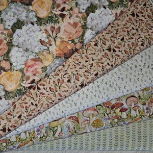 May include: A collection of floral and botanical fabric swatches. The fabrics feature watercolor-style designs of roses, hydrangeas, leaves, and mushrooms in shades of peach, cream, green, and brown. The swatches are arranged in a diagonal pattern.