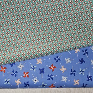 May include: Two fabric swatches. The top swatch is teal with a repeating pattern of red, white, and brown geometric shapes. The bottom swatch is light blue with a pattern of pinwheels in red, blue, and white. Ideal for quilting or sewing projects.