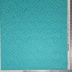 May include: Turquoise fabric with a repeating pattern of small, light green leaves. The fabric is labeled "A PAINTED GARDEN" by Lorraine Turner. The fabric is marked with measurements in inches.