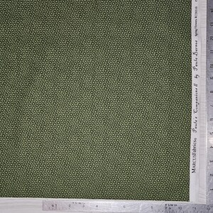 May include: Green fabric with a repeating floral pattern. The fabric is marked with the text "MARCUSFabrics Paula's Companions II by Paula Barnes Spring Flowers R220310". A ruler is placed along the edge of the fabric.