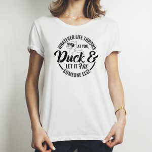 May include: White t-shirt with a black graphic design featuring a cartoon duck wearing sunglasses and the text "Whatever life throws at you, Duck & Let it Hit Someone Else."