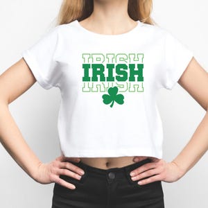 May include: White cropped t-shirt with green text that reads "IRISH" in a blocky font. A green shamrock is below the text.
