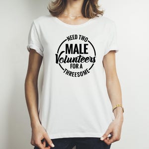 May include: White t-shirt with a black circle graphic that says "Need Two Male Volunteers For A Threesome".
