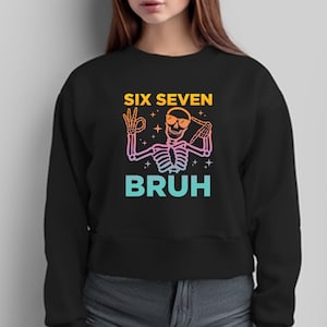 May include: Black sweatshirt with a skeleton graphic wearing sunglasses and making hand gestures. The text "SIX SEVEN BRUH" is in a gradient of yellow, pink, and blue.