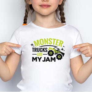 May include: White t-shirt with a green graphic that says "Monster Trucks Are My Jam" and a black and yellow monster truck illustration.