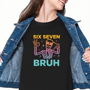 May include: Black t-shirt with a skeleton graphic wearing sunglasses and making an "okay" hand gesture. The text "SIX SEVEN BRUH" is above and below the skeleton in yellow and teal.