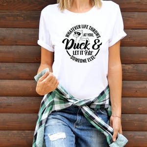 May include: White t-shirt with a black graphic of a duck wearing sunglasses and the text "Whatever life throws at you, Duck & Let it hit someone else."