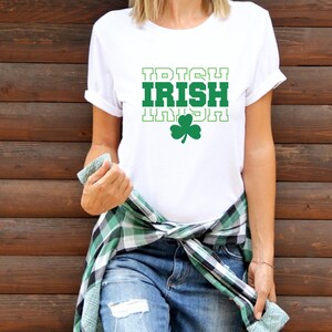 May include: White t-shirt with the text "TRISH IRISH" in green letters with a green shamrock underneath.
