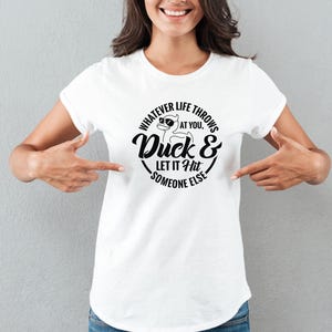 May include: White t-shirt with a black graphic print of a duck wearing sunglasses and the text "Whatever life throws at you, Duck & Let it Hit Someone Else."