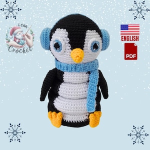 May include: Crocheted penguin amigurumi toy with black and white body, blue scarf and earmuffs. The toy is sitting on a snowy background with snowflakes. The image also includes a text overlay that says "i can crochet" and a US flag with the words "ENGLISH PDF".