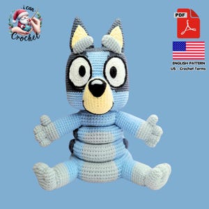 May include: A crocheted Bluey plush toy in shades of blue, gray, and yellow. The handmade toy features large black and white eyes, a yellow nose, and gray ears. The image includes text that says "i can Crochet" and "English Pattern US - Crochet Terms".