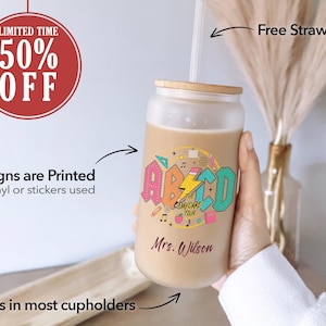 May include: A frosted glass tumbler with a colorful design featuring the letters "ABCD" and the text "The Daycare Tour". The tumbler has a wooden lid and a straw. The text "Mrs. Wilson" is printed on the tumbler.