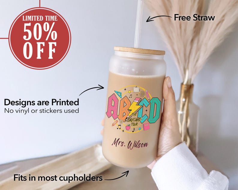 May include: A frosted glass tumbler with a colorful design featuring the letters "ABCD" and the text "The Daycare Tour". The tumbler has a wooden lid and a straw. The text "Mrs. Wilson" is printed on the tumbler.