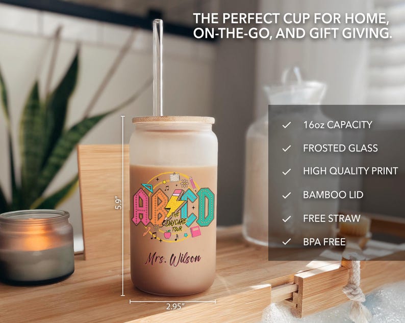 May include: A frosted glass 16 ounce tumbler with a colorful "ABCD Daycare Tour" graphic and the name "Mrs. Wilson" printed on it. The tumbler has a bamboo lid and comes with a clear plastic straw.