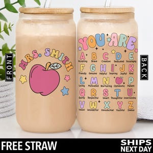 K&ouml;nnte beinhalten: Zwei 473 ml Edelstahlbecher mit Bambusdeckel und Strohhalm. Der Becher links hat einen rosa Apfel und den Text "Mrs. Smith" in Regenbogenfarben. Der Becher rechts hat den Text "You Are" in Regenbogenfarben und das Alphabet mit einem positiven Wort f&uuml;r jeden Buchstaben.