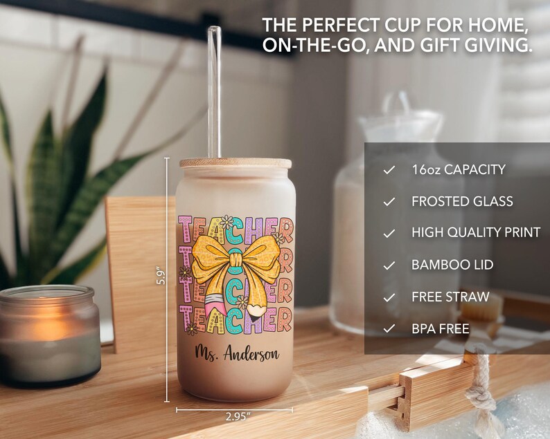 May include: A frosted glass 16 ounce tumbler with a bamboo lid and a clear straw. The tumbler has a colorful graphic of the word "Teacher" with a pencil and a bow. The tumbler is personalized with the name "Ms. Anderson".