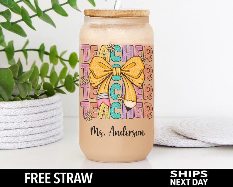 May include: A brown tumbler with a bamboo lid and a straw. The tumbler has a colorful design with the words "Teacher" and a bow with a pencil. The text "Ms. Anderson" is printed on the bottom of the tumbler.