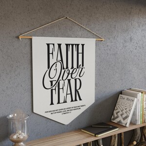 May include: White canvas wall hanging with black text that reads "Faith Over Fear" and a Bible verse from 2 Timothy 1:7.