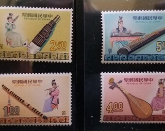 May include: Four vintage postage stamps from the Republic of China, each featuring a different traditional musical instrument and a figure playing it. The stamps are in shades of yellow, blue, and pink, with values of 100, 250, 400, and 500.
