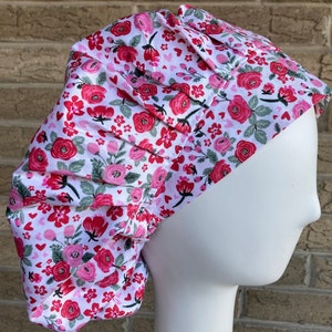 May include: A white scrub cap with a pink and red floral print featuring small hearts.