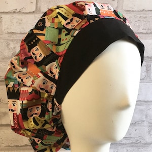 May include: A black and colorful scrub hat with a nutcracker pattern. The hat has a black band around the bottom.