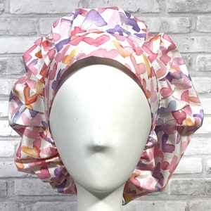 May include: A pink and white scrub hat with a watercolor heart pattern. The hat has a gathered elastic band at the back.