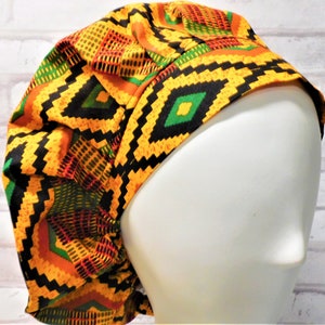 May include: A patterned bouffant scrub cap in a vibrant mix of colors. The cap features a geometric design with black, yellow, orange, and green accents. The cap is designed to cover the hair during medical procedures.