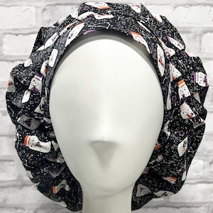 May include: Black bouffant surgical scrub cap with a repeating pattern of white potion bottles, purple accents, and constellations. The cap is designed to cover the hair and is made of a soft, flexible fabric.