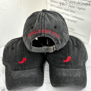 May include: Three black baseball caps with red embroidery. The front cap has the text "CB-GILLY FEST 2024" embroidered in red. The other two caps have a red chili pepper embroidered on the front.