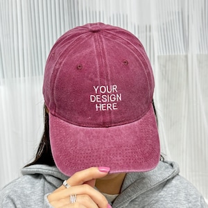 Op de afbeelding: Een bordeauxrode baseballpet met een wit geborduurd ontwerp met de tekst "YOUR DESIGN HERE".