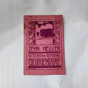 Peut inclure: Un bon d'échange vintage rose et violet avec le texte "ZEHN HELLER GUTSCHEIN der GEMEINDE GEORGENDORF". Le bon présente un design Art nouveau avec un paysage et des bordures décoratives.