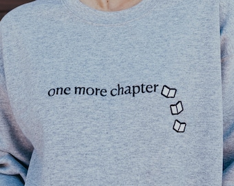 May include: A heather gray sweatshirt with the text "one more chapter" and a small graphic of three open books.