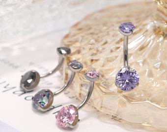 May include: Four belly button rings with different colored gems. The gems are purple, iridescent, pink, and black.