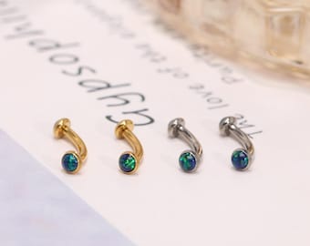Könnte beinhalten: Vier gebogene Augenbrauenpiercings. Zwei sind goldfarben und zwei silberfarben. Jeder Ring hat einen kleinen, runden, blau-grünen Opalstein am Ende. Der Schmuck wird auf einer weißen Oberfläche präsentiert.