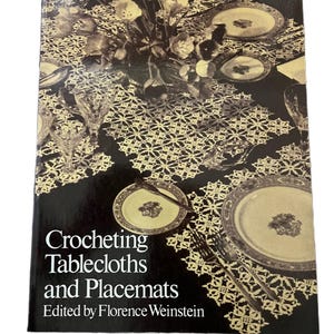 Puede incluir: Un libro vintage titulado "Crocheting Tablecloths and Placemats" editado por Florence Weinstein. La portada presenta una fotografía en blanco y negro de una mesa puesta con manteles individuales y un mantel de ganchillo.
