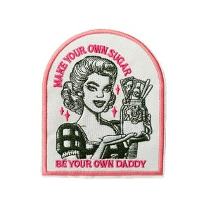 Può includere: Toppa ricamata con un'illustrazione retrò di una donna che tiene in mano un barattolo pieno di soldi. La toppa ha un bordo rosa e il testo "MAKE YOUR OWN SUGAR BE YOUR OWN DADDY."