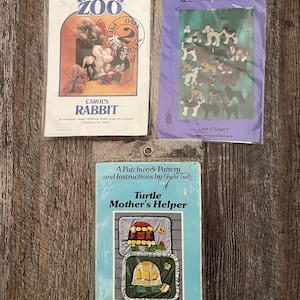 May include: Three vintage sewing pattern packets. The top left packet is labeled "Carol's Zoo" and "Carol's Rabbit." The top right packet is labeled "Loving Stitches" with dog illustrations. The bottom packet is "Turtle Mother's Helper."