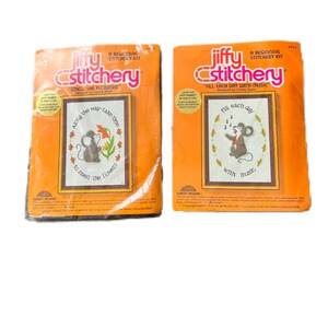 May include: Two vintage Jiffy Stitchery kits in orange packaging. The kits feature cross-stitch designs with mice. One kit says "Smell the Flowers" and the other says "Fill each day with music."