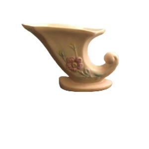 Op de afbeelding: Een vintage, crèmekleurige keramische hoorn des overvloeds vaas. De vaas heeft een gebogen vorm met een bloemmotief in roze en groen. De vaas is ongeveer 18 cm lang en 13 cm hoog.