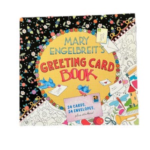 Puede incluir: Un libro cuadrado titulado "Mary Engelbreit's Greeting Card Book" con un fondo negro adornado con flores blancas y hojas verdes. La portada presenta un círculo amarillo con el título, dos pájaros azules y el texto "24 tarjetas, 24 sobres, más pegatinas!"