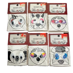 May include: Six packages of novelty googly eyes for crafts. Each package contains a pair of eyes with different colors and designs. The packages are labeled "Novelty Eyes" and "Fibre Craft".