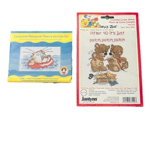 Op de afbeelding: Twee kruissteekpakketten. Eén is blauw en geel met een kat in een boot. De andere is rood en wit met de tekst "After 40 it's just patch, patch, patch" en twee teddyberen.