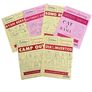 May include: A set of six pink and yellow embroidery transfer sheets with various designs, including a cat, a butterfly, a songbird, a camp scene, and a Day of the Dead scene. Each sheet includes instructions and is 8.5 x 11 inches.