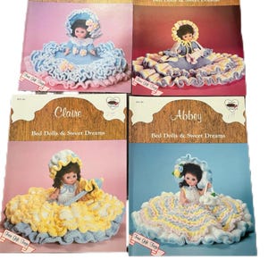 May include: Four vintage doll patterns, each featuring a doll in a crocheted dress. The patterns are titled "Sarah," "Eva," "Claire," and "Abbey." Each doll is wearing a different colored dress, with the text "Bed Dolls & Sweet Dreams" on each pattern.